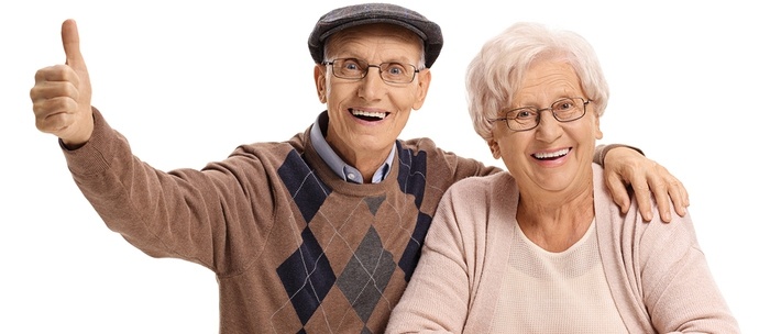 Senior man and woman smiling and giving thumbs up.