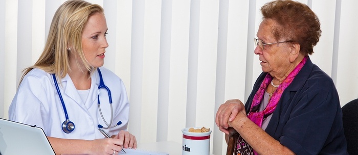 Medical doctor consoling with an older female patient.